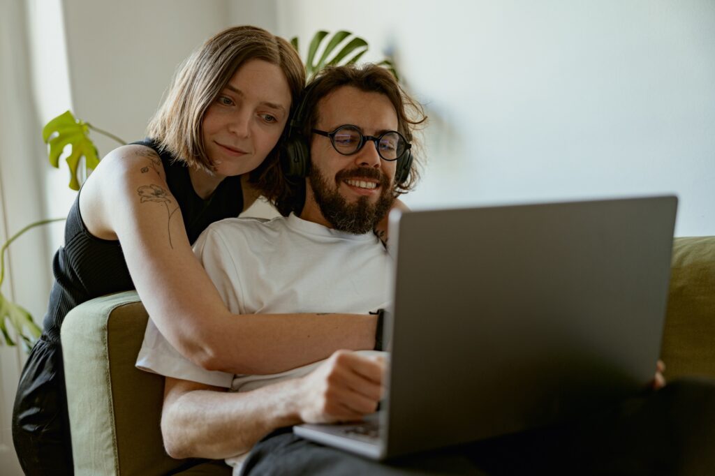 Gentle couple is hugging and looking video on laptop together at home. Family time